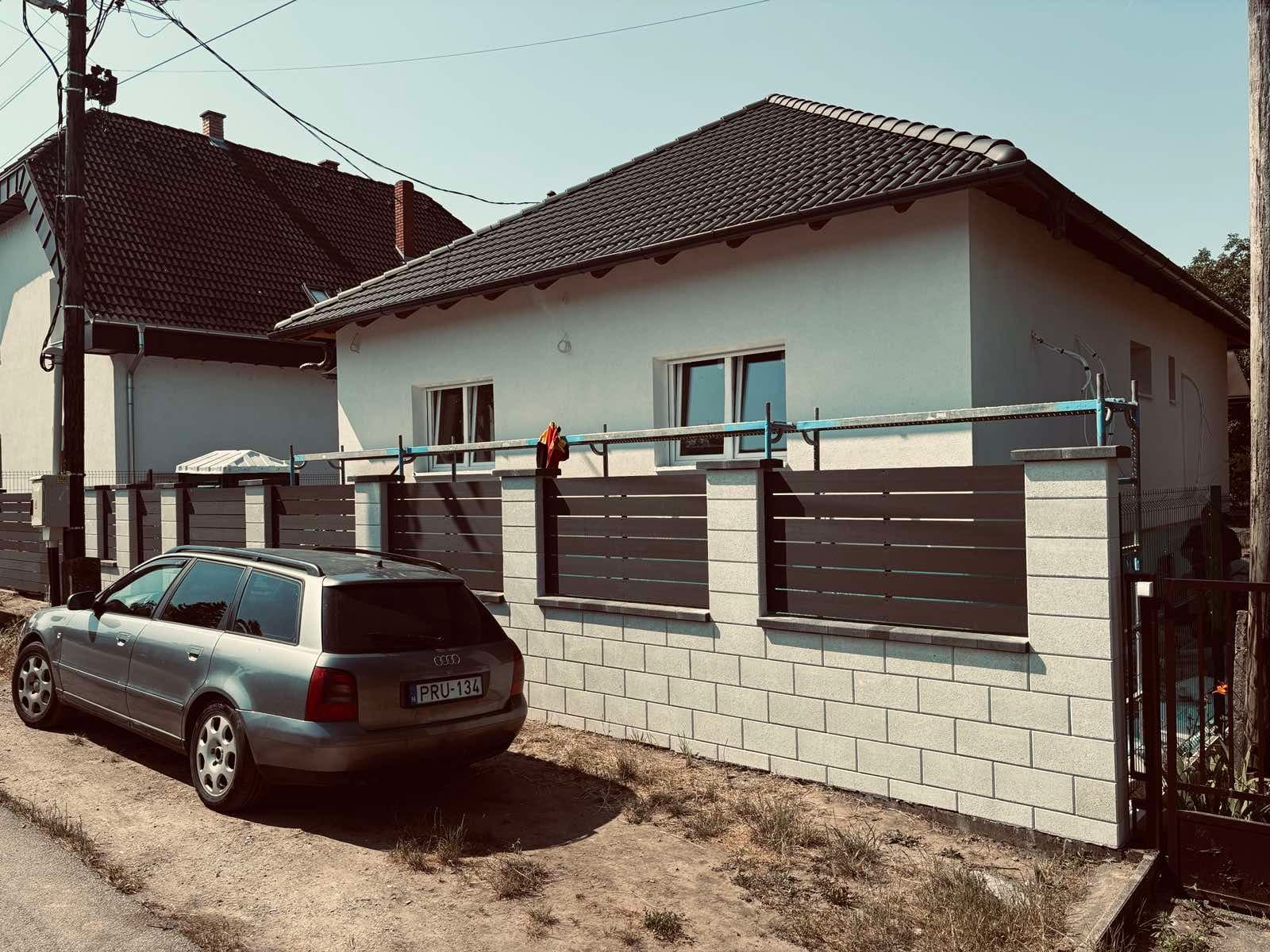 Elkészült földszintes családi ház az utca felől, kontyolt cseréptetővel és kész kerítéssel